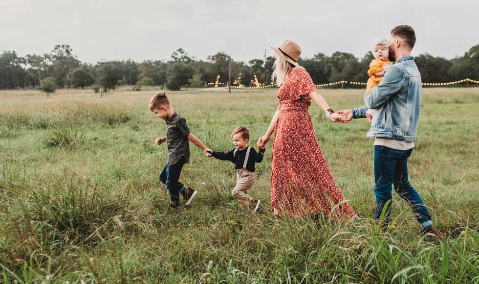 Young family of five walking through a grassy field