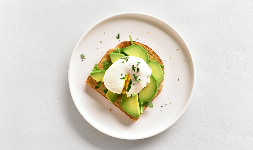Avocado and egg on toast on a white plate