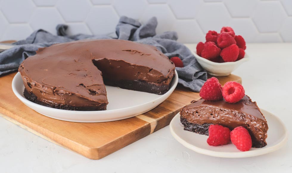 Chocolate avocado and almond mousse cake with fresh raspberries on a white plate