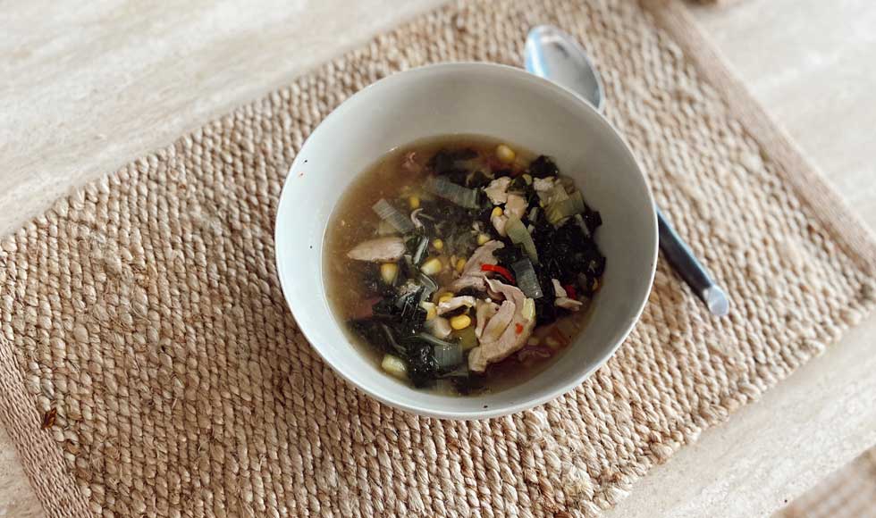 Bowl of chicken, ginger and corn nourishing soup on a woven place-mat