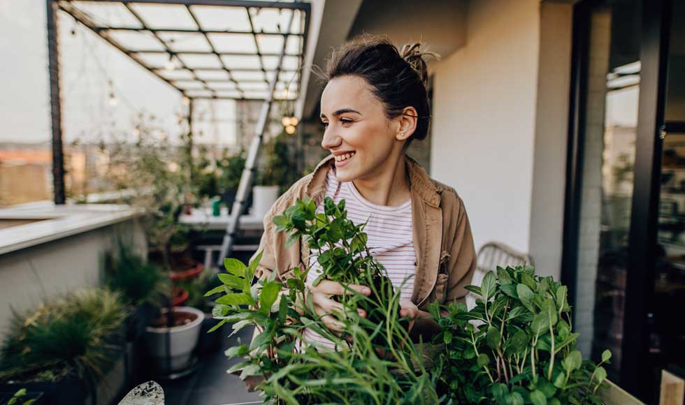  Young woman taking care of the plants in her rooftop garden